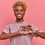portrait of happy african woman confesses in love shows heart gesture smiles broadly has